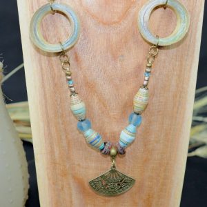 Collier long, composé de plusieurs perles en papier roulé bleutées; de perles de rocailles dorées; et de deux grands anneaux en papier roulé. Il y a un pendentif en forme d'éventail, de couleur bronze