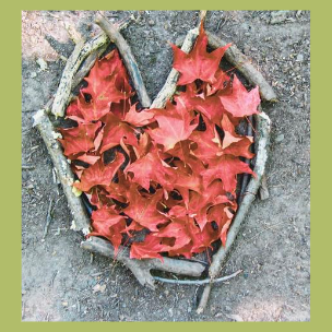 Coeur fait avec des branches posées au sol et comblé de feuilles d'arbre rouges