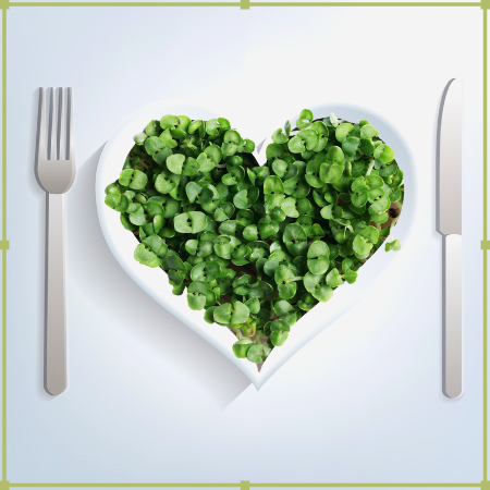 Assiette en forme de coeur avec des la salade dedans. et un couteau et une fourchette. Pour une repas écologique