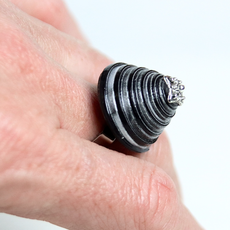 bague en papier noir portée sur la main gauche pour montrer l'échelle du bijou