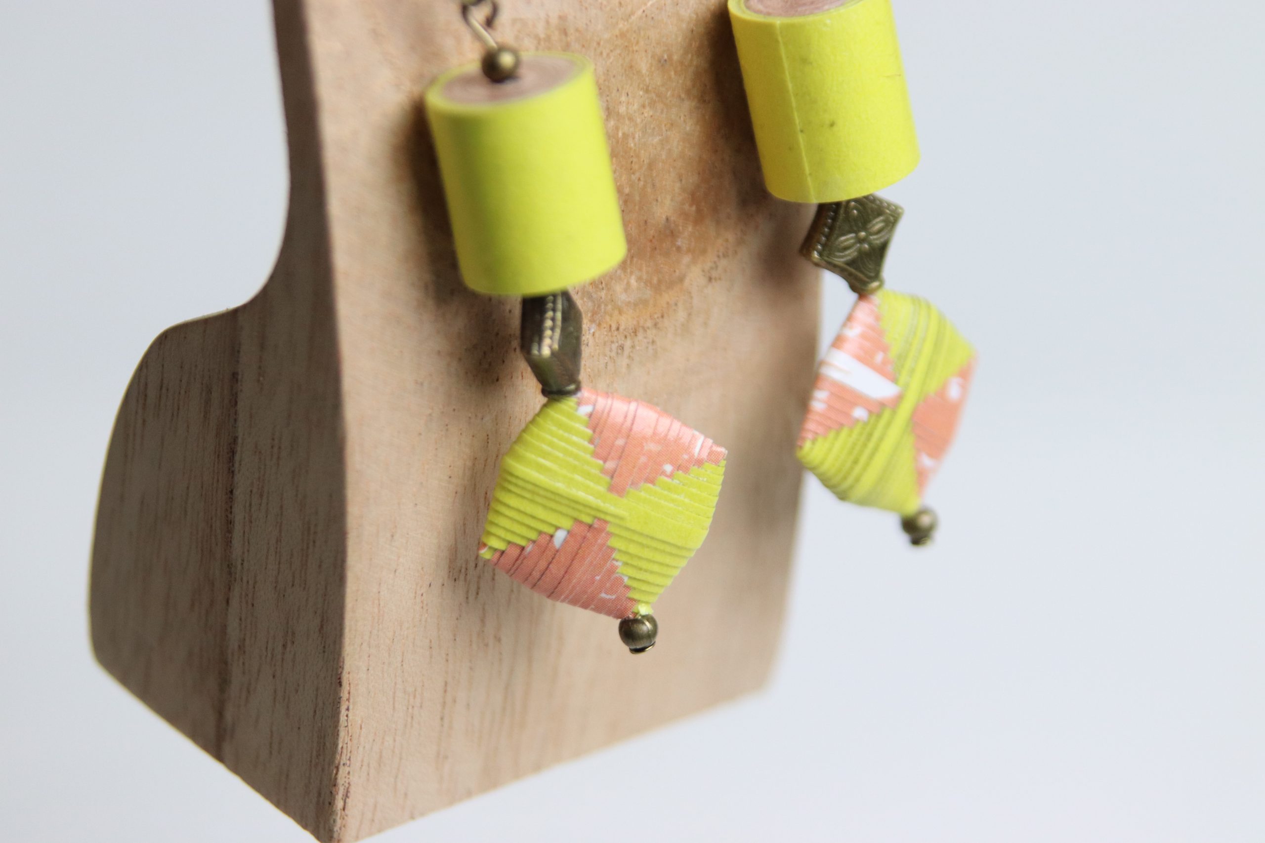 Boucles d'oreilles avec une perle roulée cylindrique et une perle pliée toutes les deux de couleur jaune et saumon et fabriquées en papier